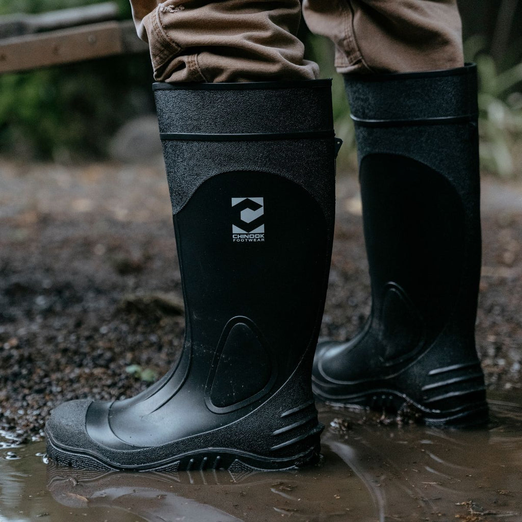 Side view of Battleaxe Regrind 15" Men's Waterproof Rubber Boots in a puddle. The boots feature a tall, durable design with reinforced soles, built for wet and muddy environments, perfect for tough outdoor tasks.