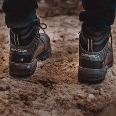 Rear view of the Pallet Jack 6" Comp Toe Men’s Waterproof Work Boot in Black, displaying the 'Chinook' logo on the heel. The boots feature a rugged design with diamond-patterned reinforcement and thick outsoles, shown on a sandy, dirt-covered surface, emphasizing their durability and strength for tough environments.