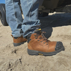 A guy in Maverick 6” Comp Toe Men’s Waterproof Work Boots in wheat stands firmly in the sand. These rugged boots, featuring reinforced toes and solid soles, are built to tackle anything the job or the outdoors throws your way.